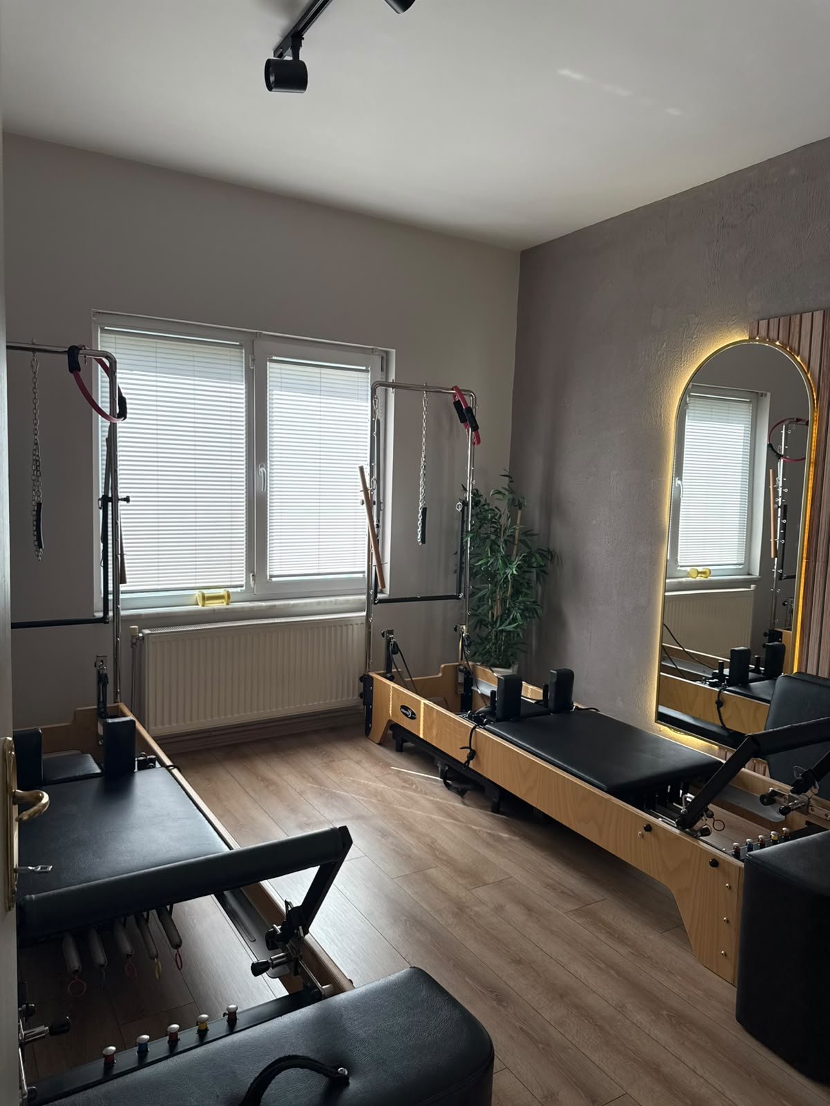 Pencere yanında ahşap reformer cihazları ve ışıklı ayna