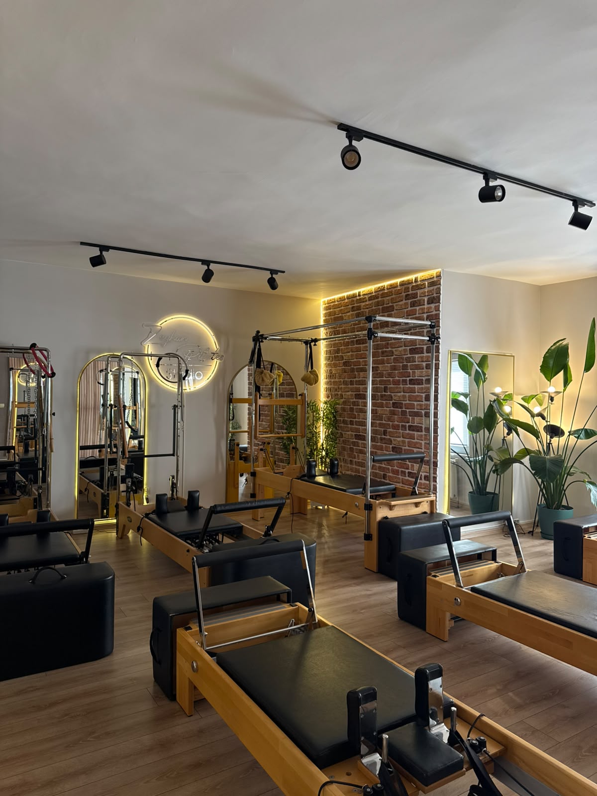 Zeyhan Pilates salonunda reformer cihazları, aynalar ve aydınlatılmış tuğla duvar